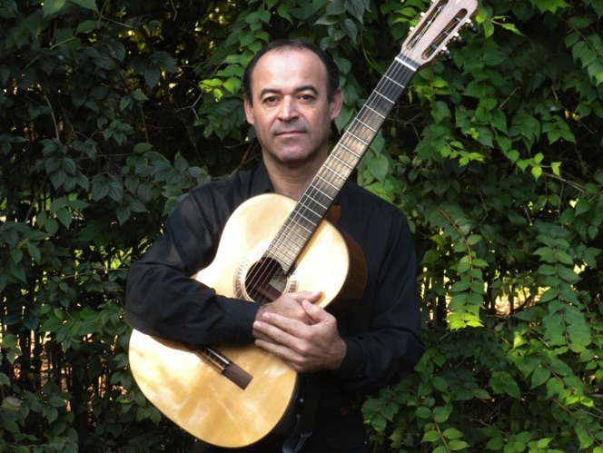 Antonio Cosenza mit Gitarre vor grünem Blattwerk
